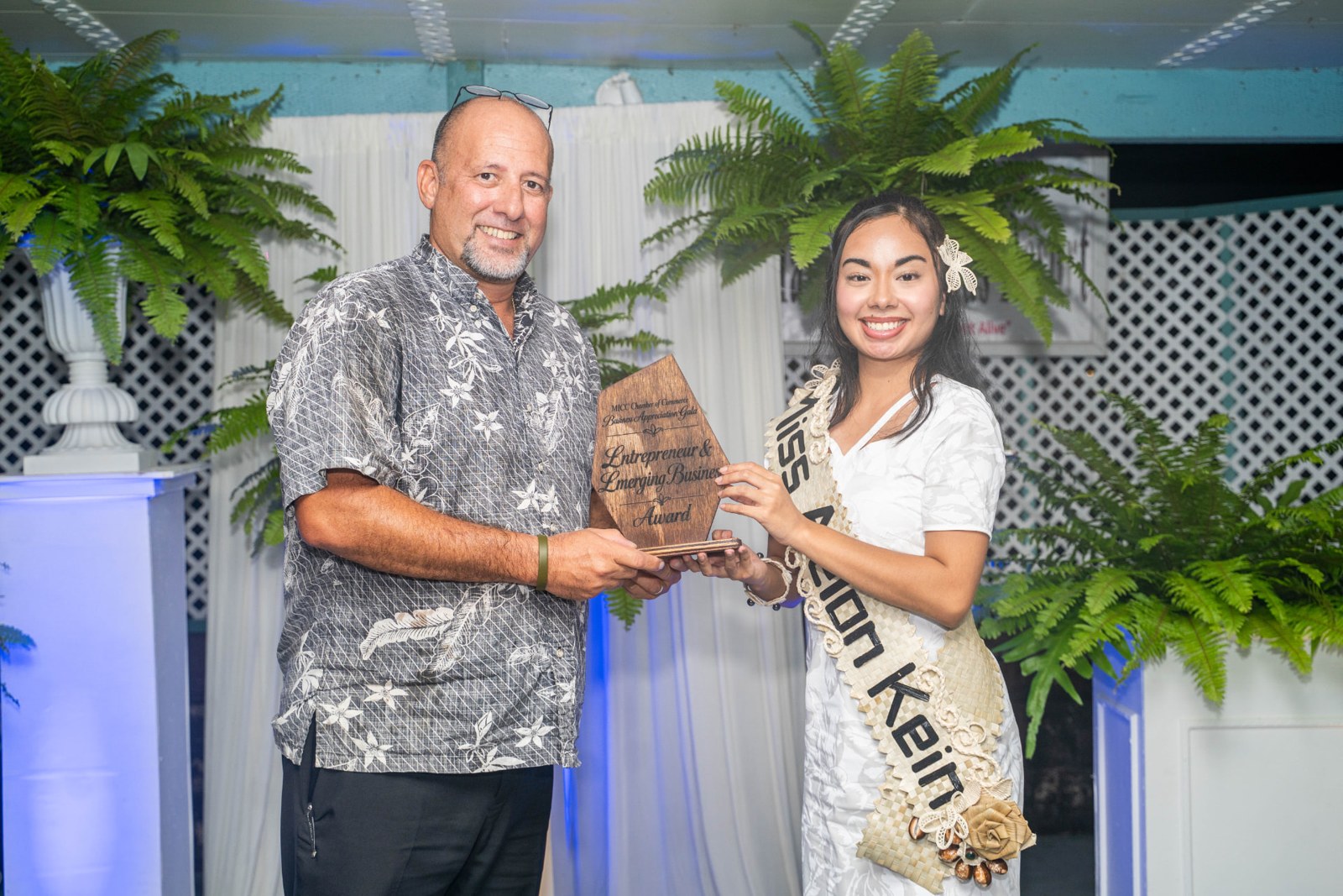 Two people holding a business award at an event