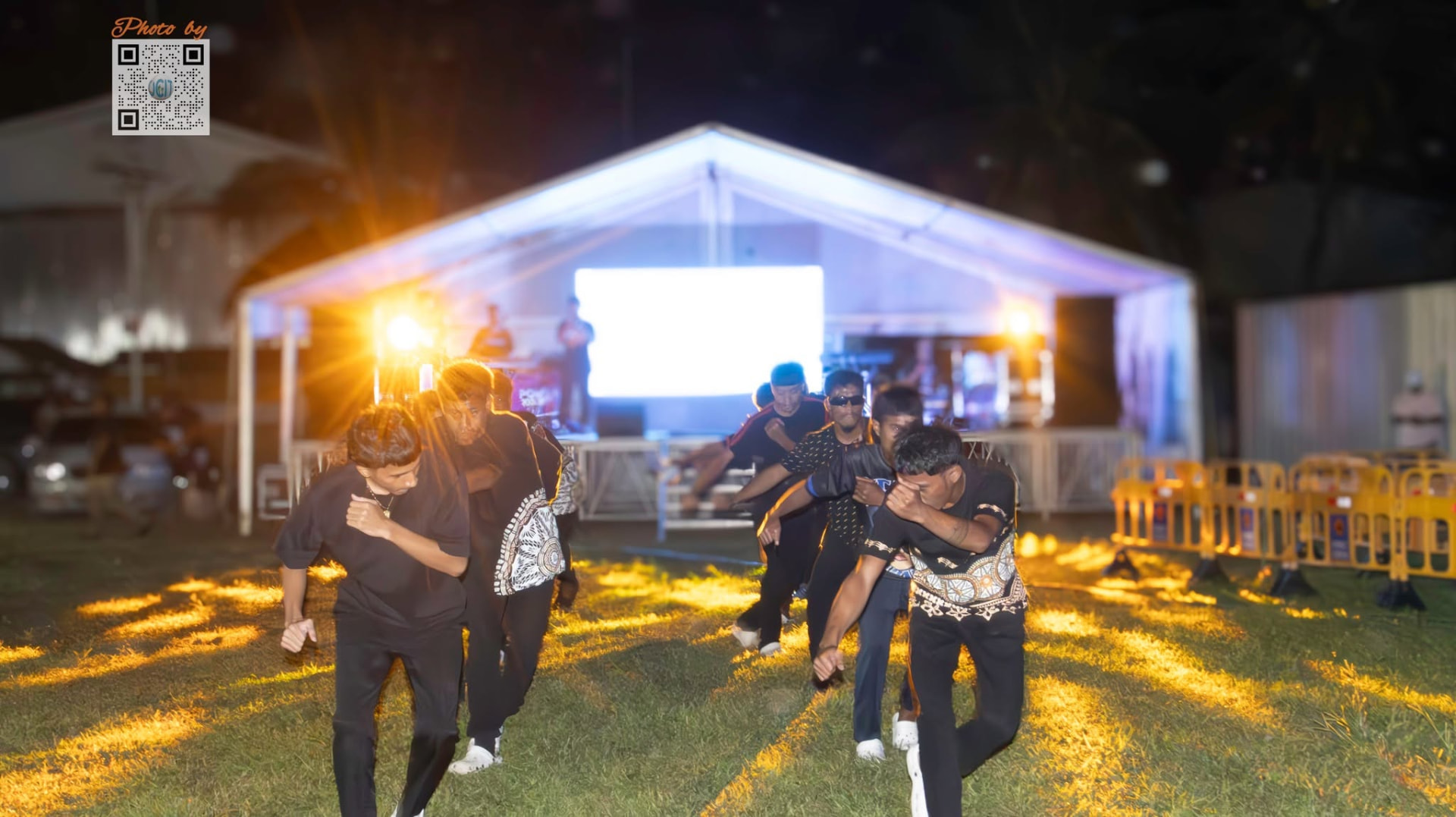 Dancers performing at an outdoor evening event under lights