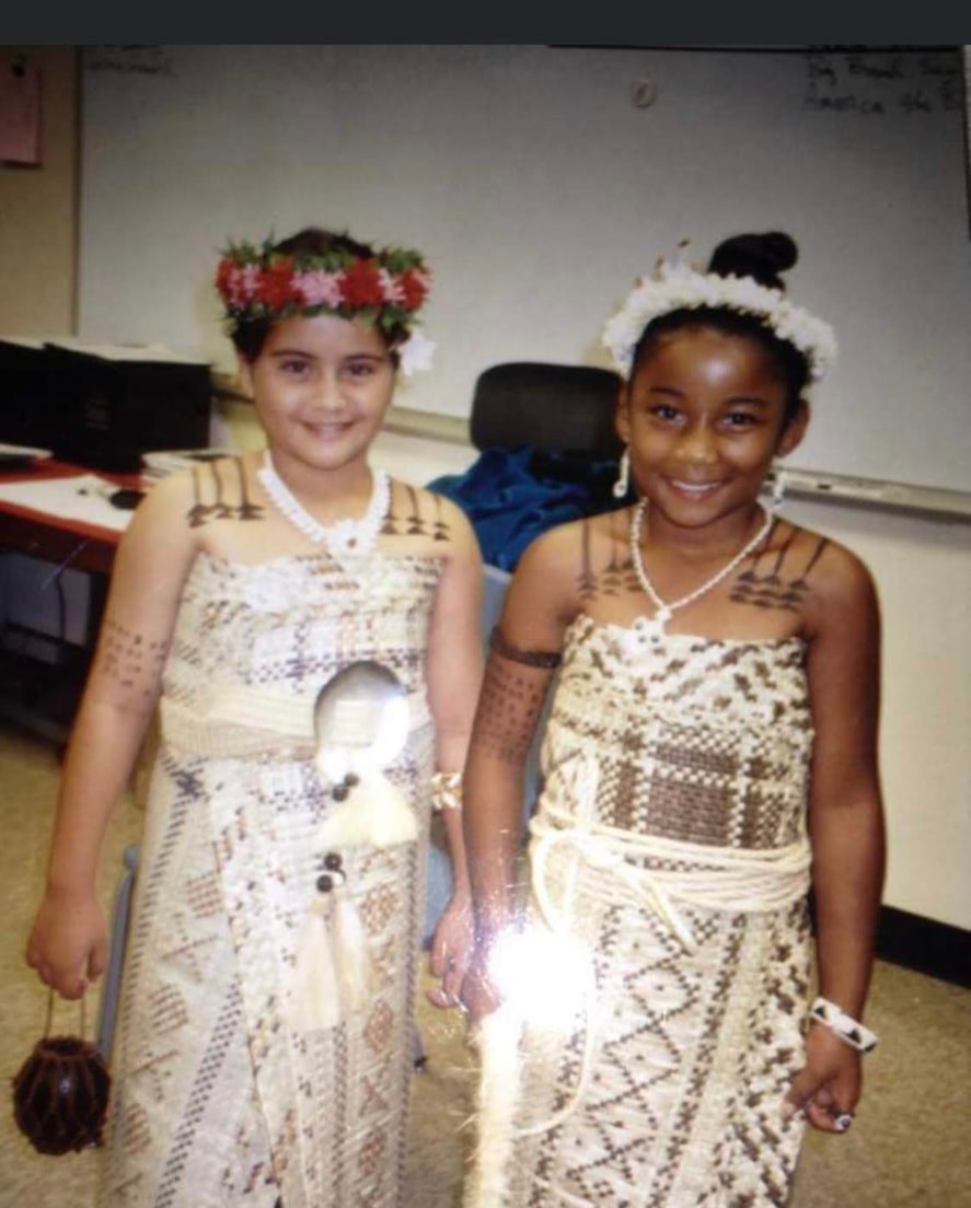 Two smiling children wearing woven traditional dress and flower crowns
