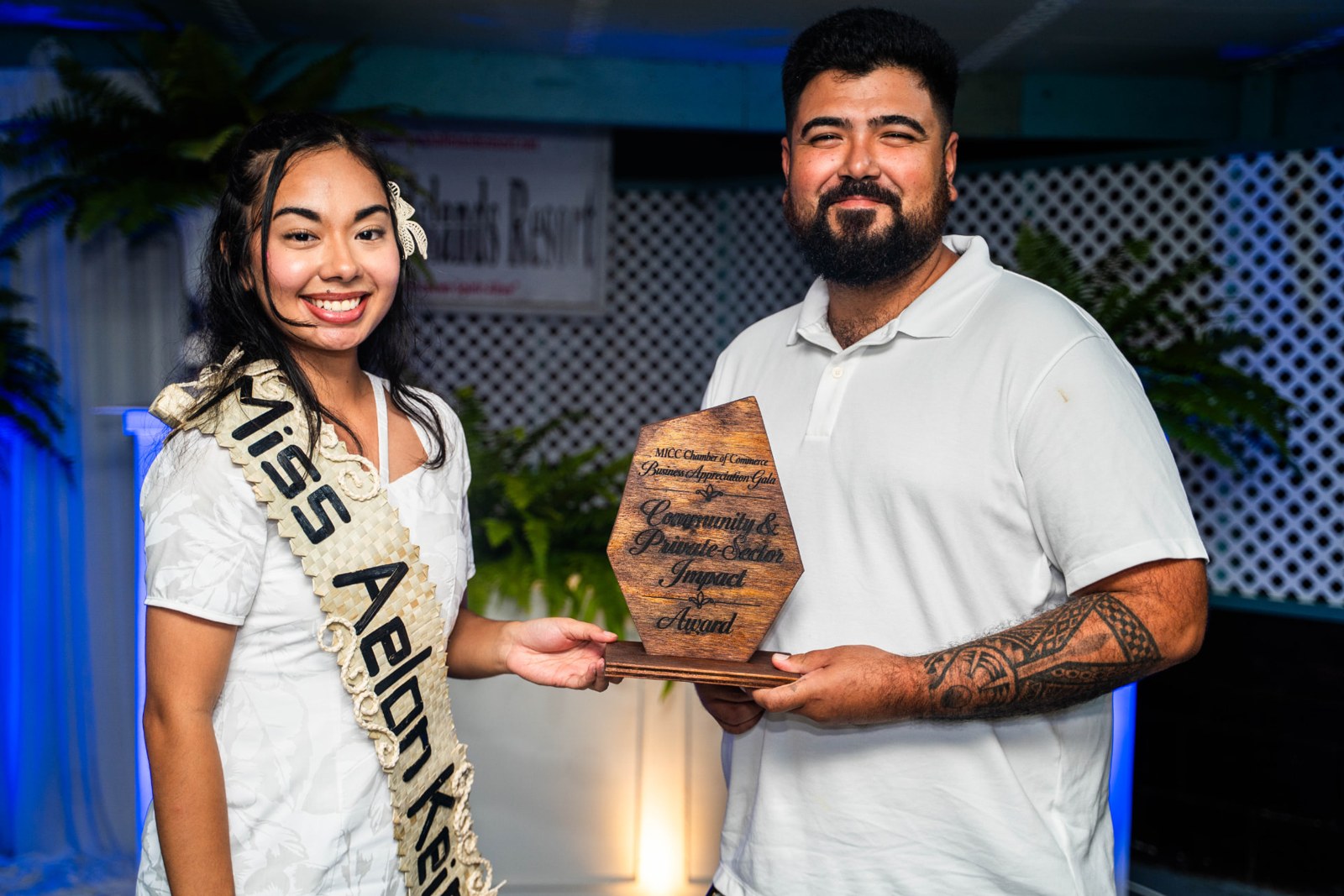 Two people holding a community impact award at an event